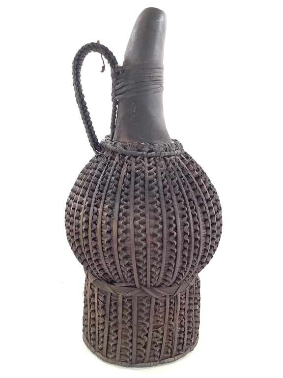 Cameroon Grassland Palm Wine Gourd w Woven Rattan: 10 1/2"Dia., 22 1/2"H. Woven rattan / cane over gourd with undulating openwork pattern. 1" chip at top lip of gourd. Provenance: Collection of William and Diane Itter. Please see photos for condition