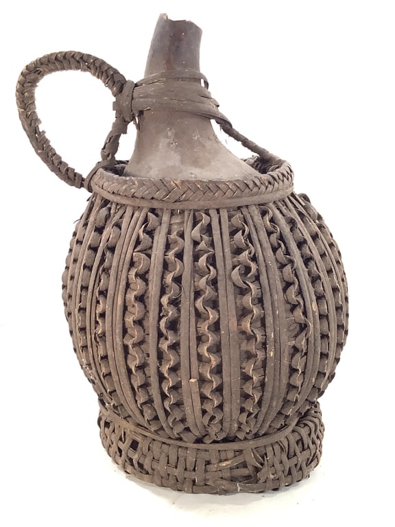 Cameroon Grassland Palm Wine Gourd Rattan: 8" Dia. x 13 1/2"H. Woven rattan / cane over gourd with undulating openwork pattern. Chips at top edge of gourd spout. Provenance: Collection of William and Diane Itter. Please see photos for