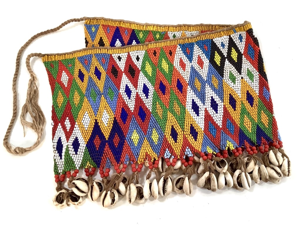 Kirdi Beaded Apron Cameroon Diamond Grid: 21"W x 8 1/2"H excluding tie. Kirdi beaded apron with a geometric diamond grid pattern and beaded fringe of glass beads and cowrie shells. Minor wear on the tie. Provenance: Collection of William and 