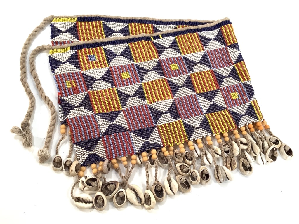 Kirdi Beaded Apron Cameroon: 21"W x 8 1/2"H excluding tie. Kirdi beaded apron with a geometric diamond trellis & stripped squares pattern and beaded fringe of glass beads and cowrie shells. One missing cowrie shell on the