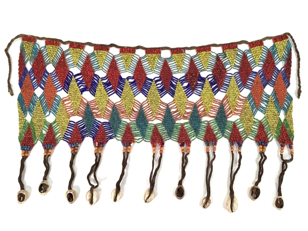 Kirdi Beaded Apron Cameroon w Open Weave: 16 1/2"W x 9 1/2" excluding tie. Kirdi beaded apron with a geometric diamond grid pattern with open weave between diamond. Beaded fringe of glass beads and cowrie shells. Provenance: Collection of