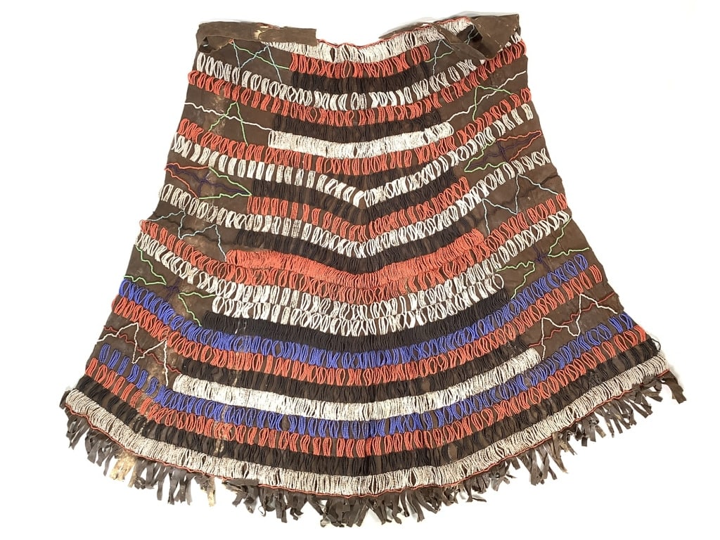 Maasai Womens Leather Beaded Skirt Kenya: 24"W at top excluding tie, 33"L at center, 45 1/2" circumference at bottom (excluding fringe). Beaded leather skirt with leather fringe. Provenance: Collection of William and Diane Itter. Please see