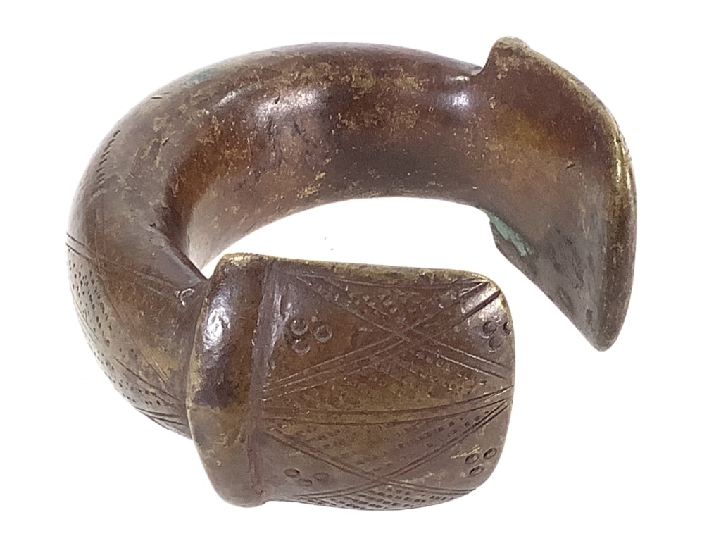 African Currency Bangle Bronze Alloy: 3 3/8"W x 3 "D x 1 1/2"H. Currency bangle bracelet of bronze alloy with a brown/ gold patina and a geometric incised pattern. Provenance: Collection of William and Diane Itter. Please see photos for