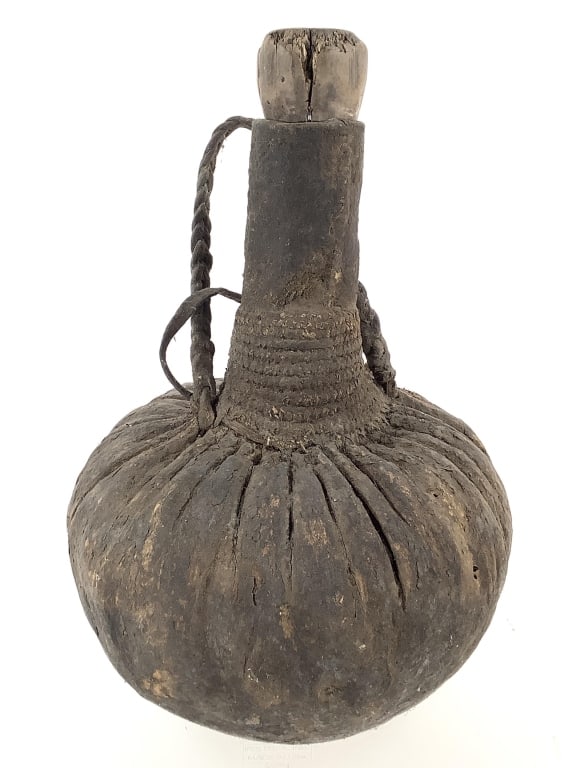 Turkana Skin Jar East African Kenya: 13 1/2"H x 9 5/8"D. Butter fat container, animal skin covered gourd with wood stopper. Wood stopper has some chips at top edge. Provenance: Collection of William and Diane Itter. Please see photos for