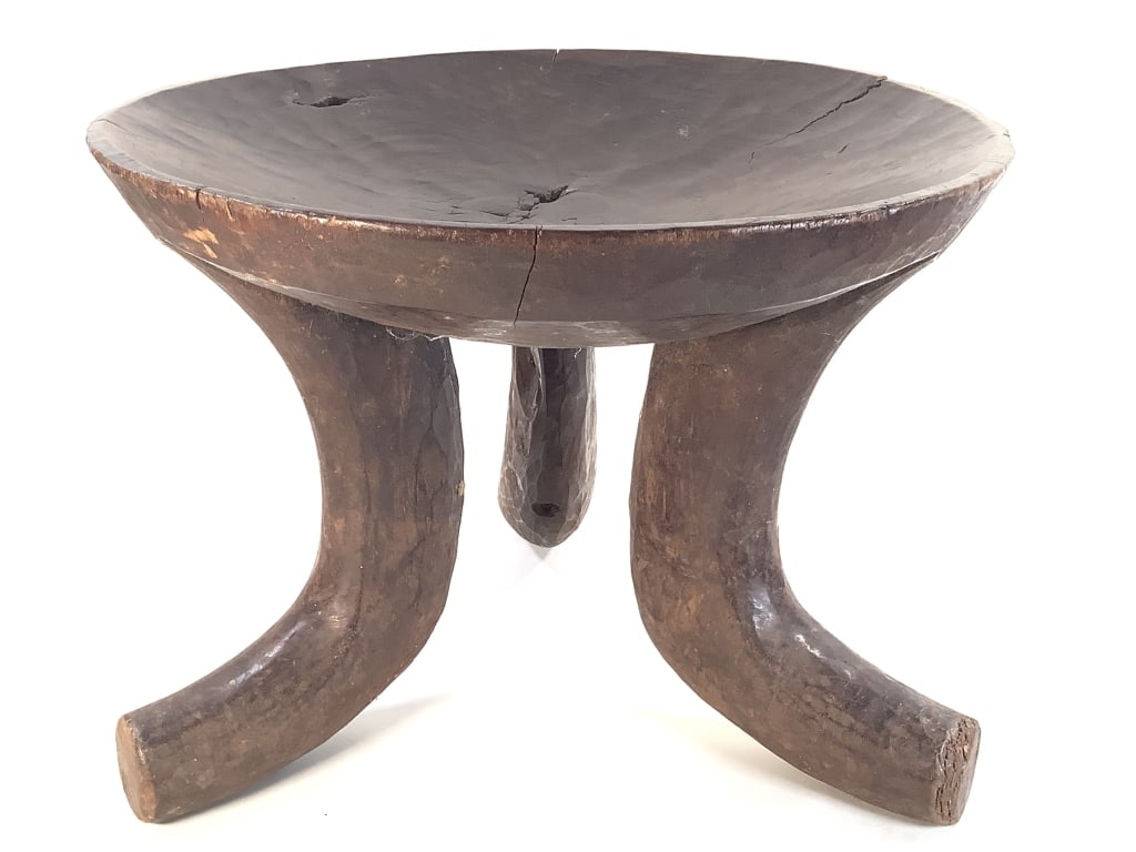 Hand-Carved Oromo Wooden Stool Ethiopia: 18 1/4"Dia., 13 1/2"H. Fissures in seat, some natural imperfections of wood. wear at the edges of the feet and rim of seat. An East African piece likely from the Oromo People of Ethiopia. Provenance: