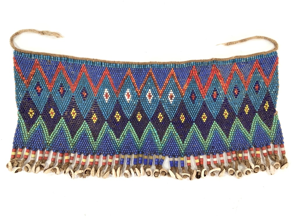 Kirdi Beaded Apron Cameroon: 19 1/2"W x 8 3/4"H excluding apron tie. Kirdi beadwork apron with an intricate diamond weave pattern with cowrie shell and bead fringe. Larger 1/8" beads on the weaving and nearly 1/4" beads on the fr