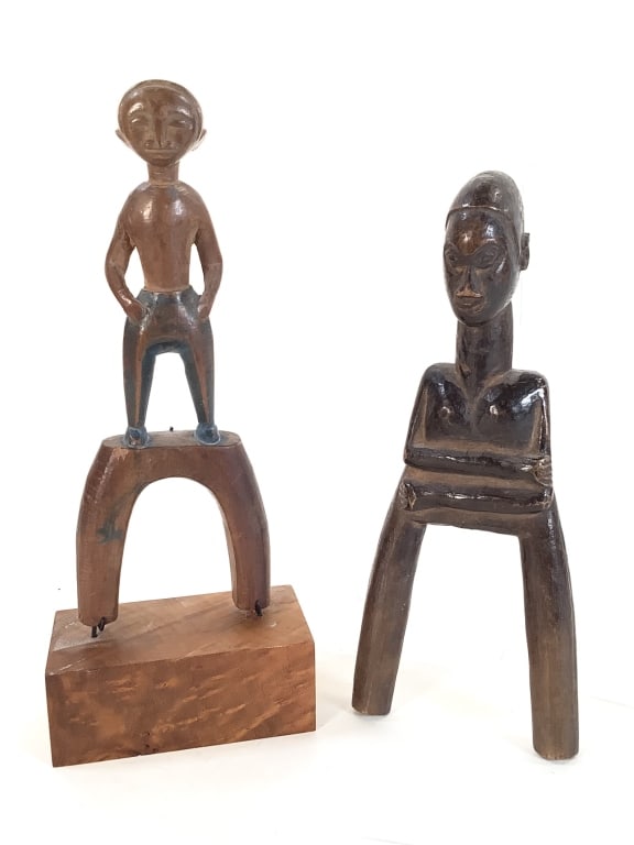 2 Baule Sling Shot Carved Wood Figure Ivory Coast: 2 carved wood sling shots. Larger, 8 3/8"H x 3 1/4"W. Sling shot with stand, 9 3/8"H. Provenance: Collection of William and Diane Itter. Please see photos for condition and details.