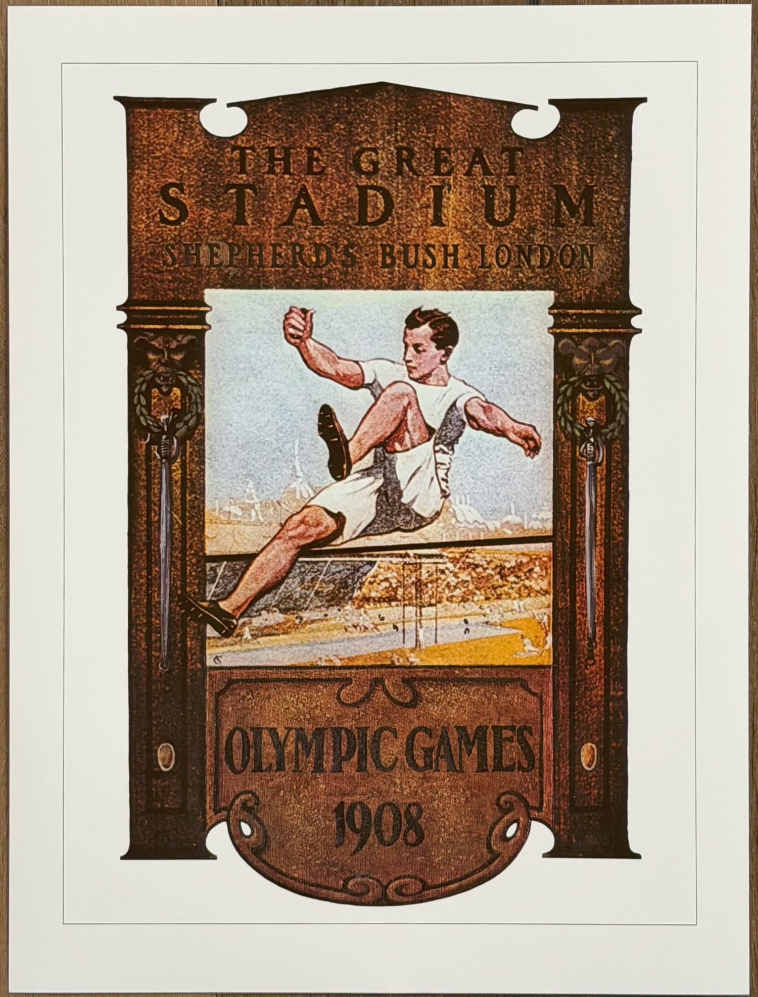 1908 London Olympic Games Poster – Great Stadium Shepherd’s Bush Print: Official licensed print of the 1908 London Olympic Games poster. Features a hurdler athlete mid-jump inside an ornate architectural frame with the text “The Great Stadium Shepherd’s Bush London&rd