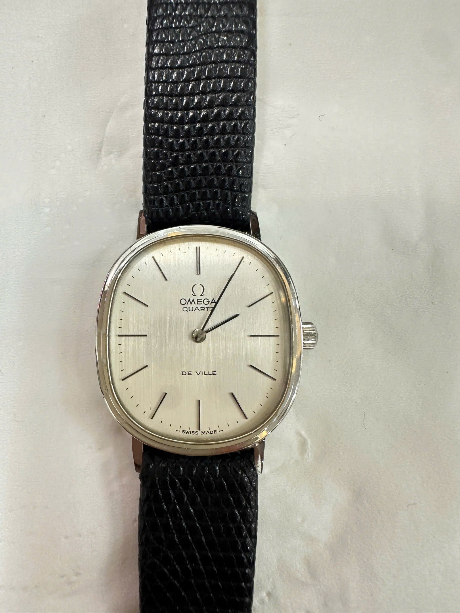 Omega De Ville Quartz Wristwatch, Swiss Made: Classic Omega De Ville quartz wristwatch featuring a silver dial with applied baton markers, signed Omega Quartz – De Ville – Swiss Made.Slim rectangular case, stainless steel, fitted with a black