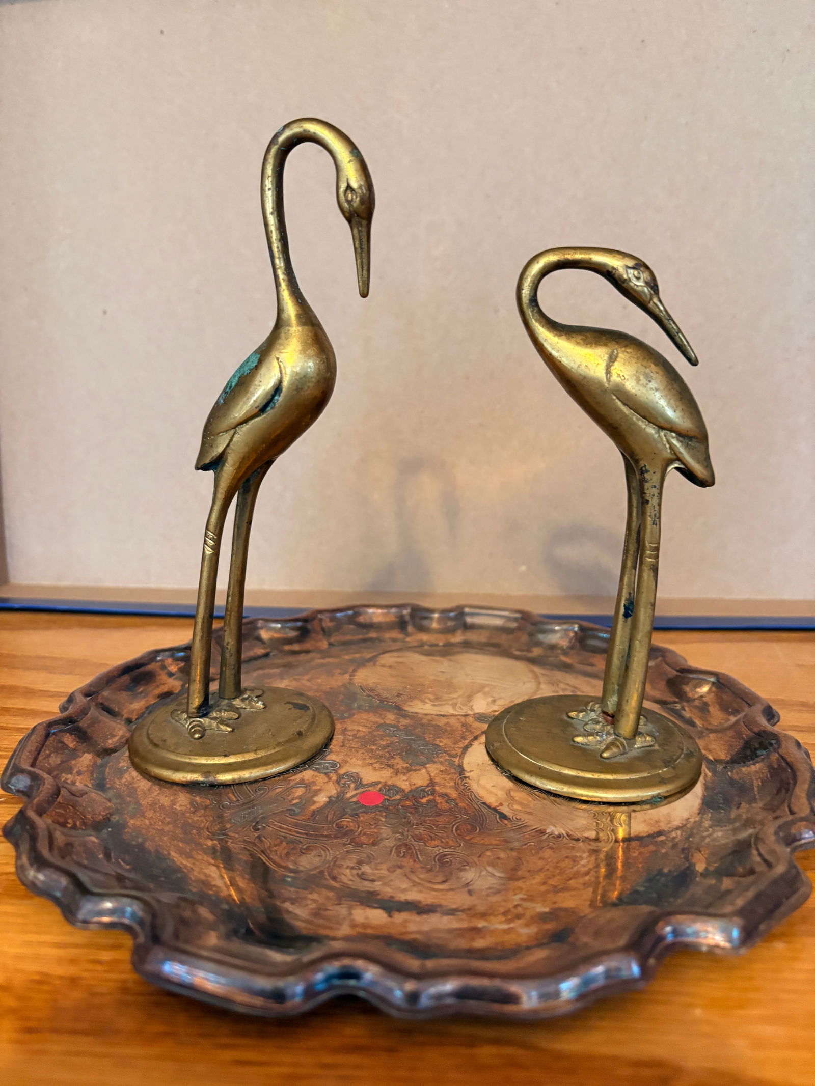 Pair of Brass Crane Figurines with Decorative Tray: Elegant pair of cast brass crane figures, finely modeled with elongated necks and slender legs, mounted on individual round bases. Presented together with a scalloped-edge decorative metal tray