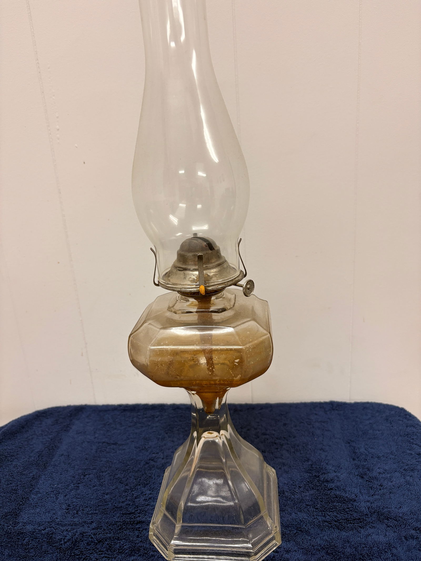 Victorian Cut Glass Kerosene Table Lamp: A late 19th–early 20th century kerosene table lamp featuring a faceted clear glass font and sharply paneled pedestal base. Fitted with a period metal burner and adjustment wheel, retaining an attrac