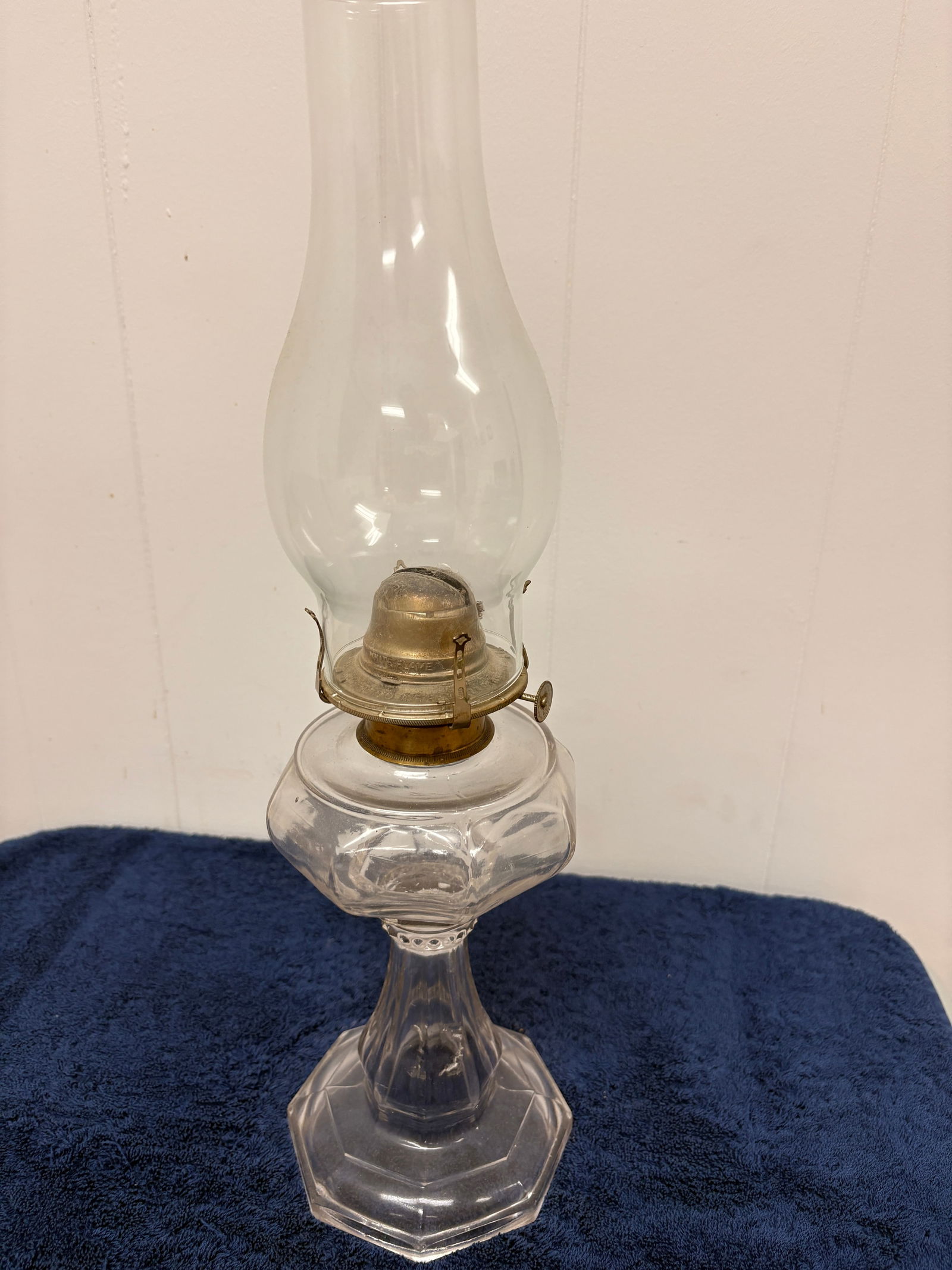 Canadian Pressed Glass Kerosene Table Lamp, c. 1890–1910: Elegant antique kerosene table lamp featuring a clear pressed-glass font with faceted panels, rising to a fluted stem and octagonal base decorated with starburst motifs. Fitted with an original brass