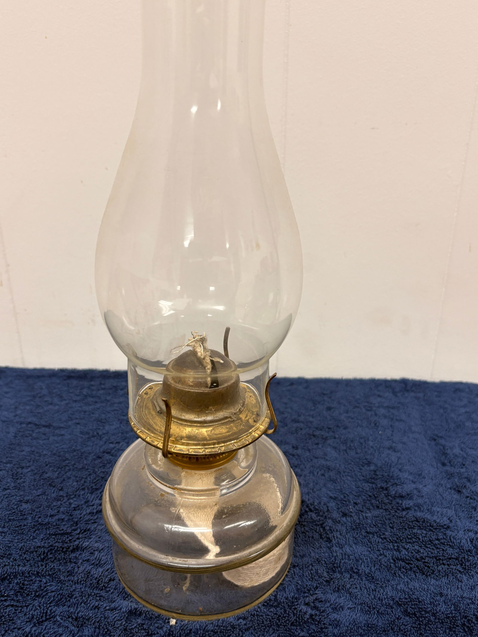 Victorian Pressed Glass Oil Lamp with Original Burner: Late 19th century clear pressed-glass oil lamp, featuring a rounded reservoir with subtle molded details and a faceted pedestal base. Fitted with an original brass burner and chimney; wick present. Di