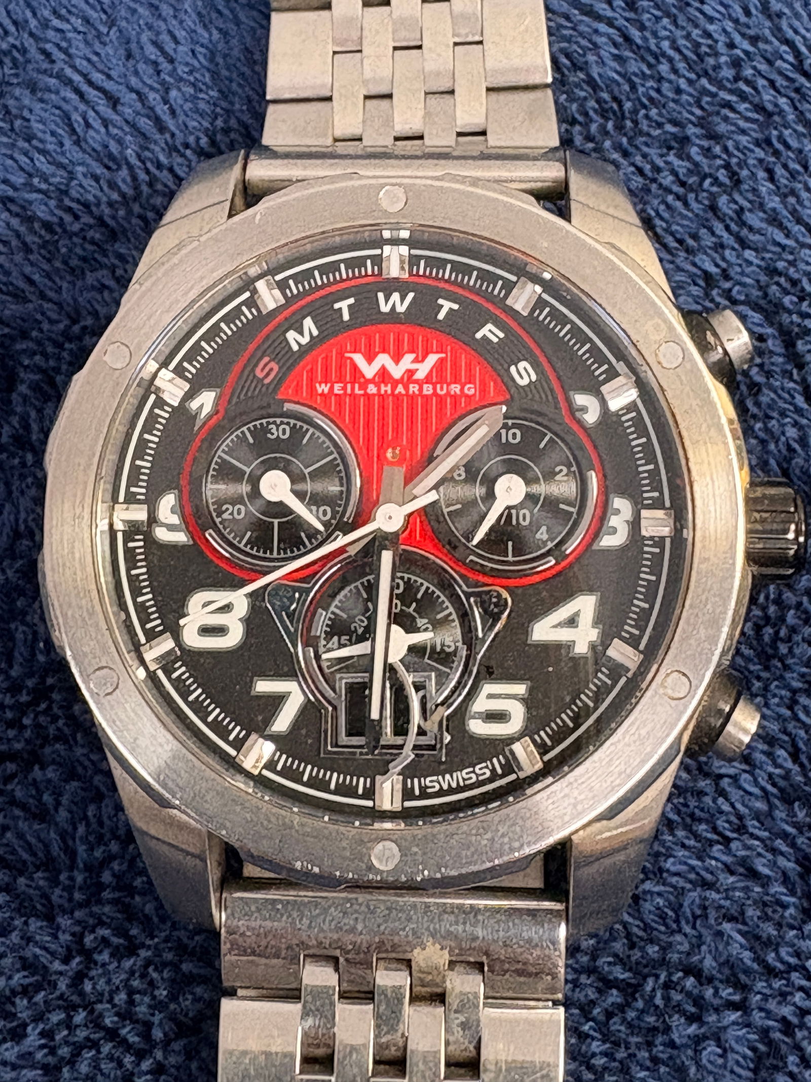 Weil & Harburg Multi-Function Wristwatch (Unworn): Weil & Harburg Swiss wristwatch featuring a black dial with red accent center, three subdials, and day-of-week display along the upper chapter ring. Brushed stainless steel case and bracelet with