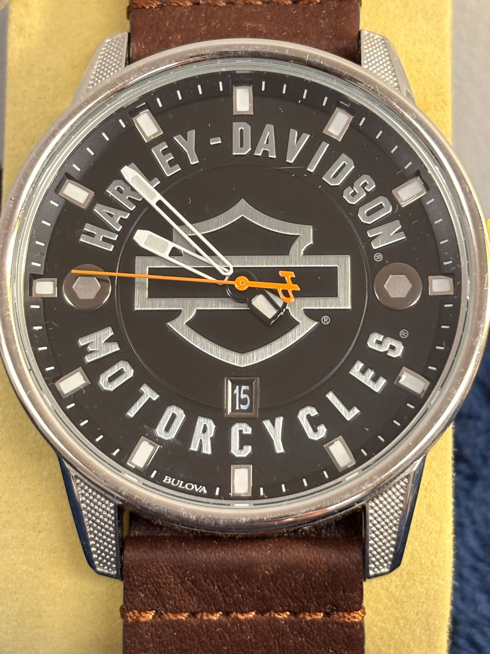 Bulova Harley-Davidson Wristwatch: Bulova for Harley-Davidson men’s wristwatch featuring a black dial with large Bar & Shield logo, orange sweep seconds, and date at 6 o’clock. Stainless steel case with textured lugs and brown