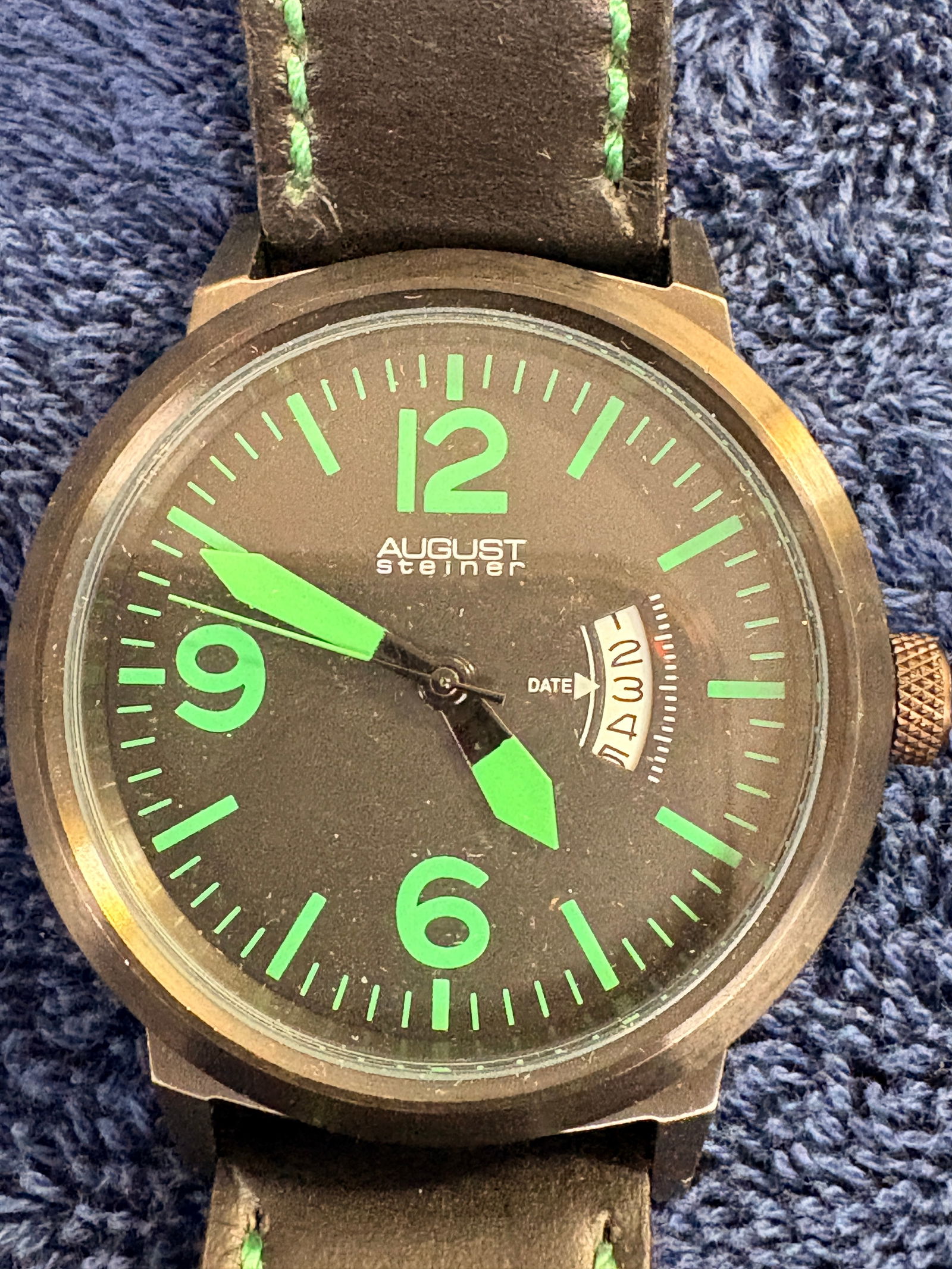 August Steiner Black & Green Luminous Wristwatch: Bold August Steiner quartz watch with black dial and bright green luminous numerals and hands, date display, and dark stainless steel case. Mounted on black leather strap. Approx. 45 mm case. In good