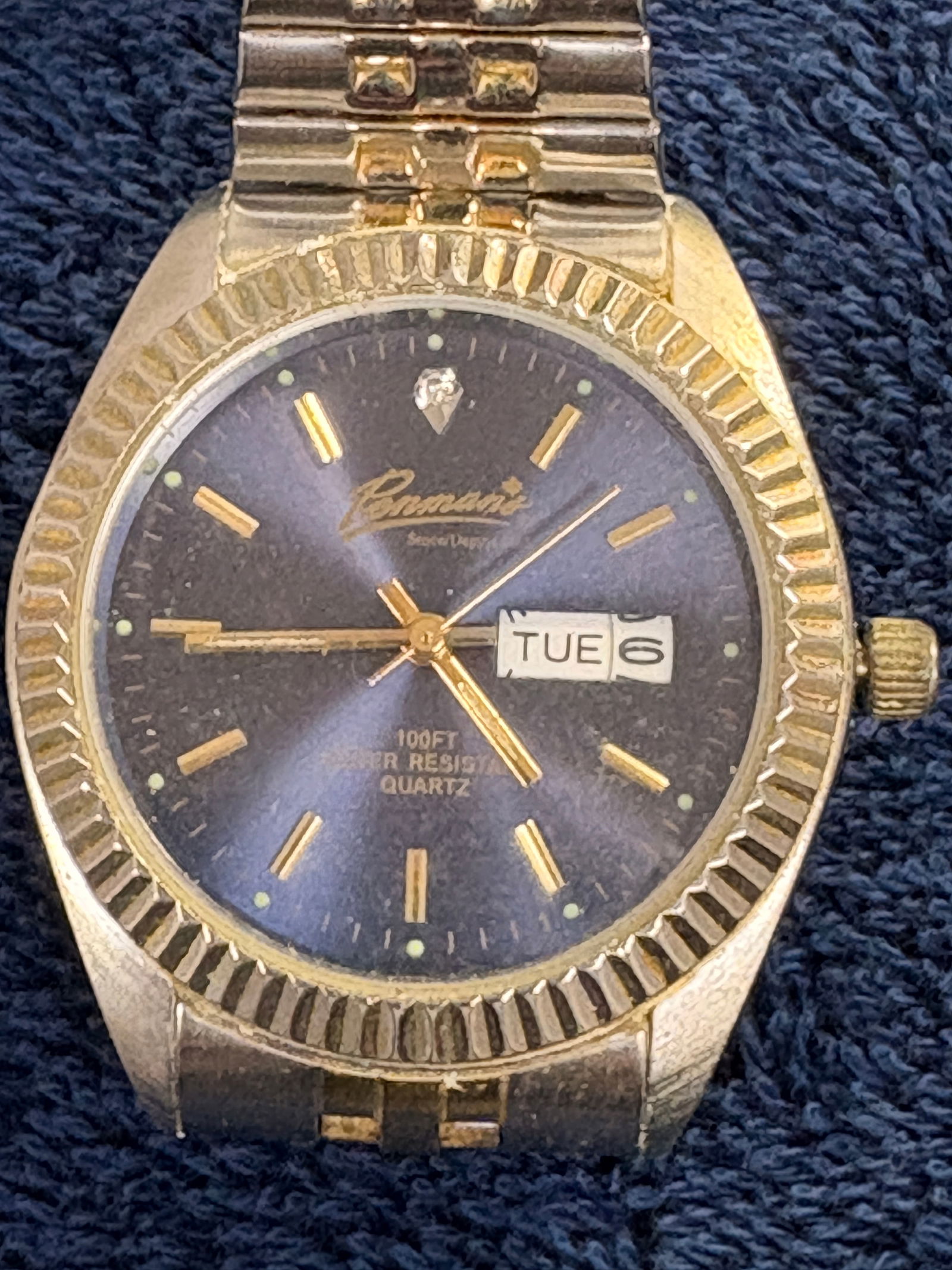 Renisante Day-Date Quartz Wristwatch, Two-Tone Bracelet: Vintage Renisante quartz wristwatch featuring a dark sunburst dial with applied gold-tone markers and day-date display at 3 o’clock. Marked “100 FT Water Resistant Quartz.” Fluted gold-tone