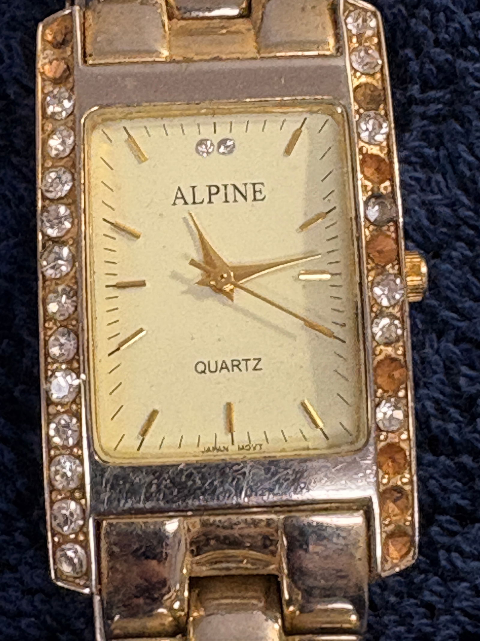 Alpine Quartz Ladies Gold-Tone Crystal Bezel Watch: Elegant women’s wristwatch by Alpine featuring a rectangular gold-tone case with crystal-set bezel and matching bracelet. Quartz movement for reliable timekeeping. Classic dress style with