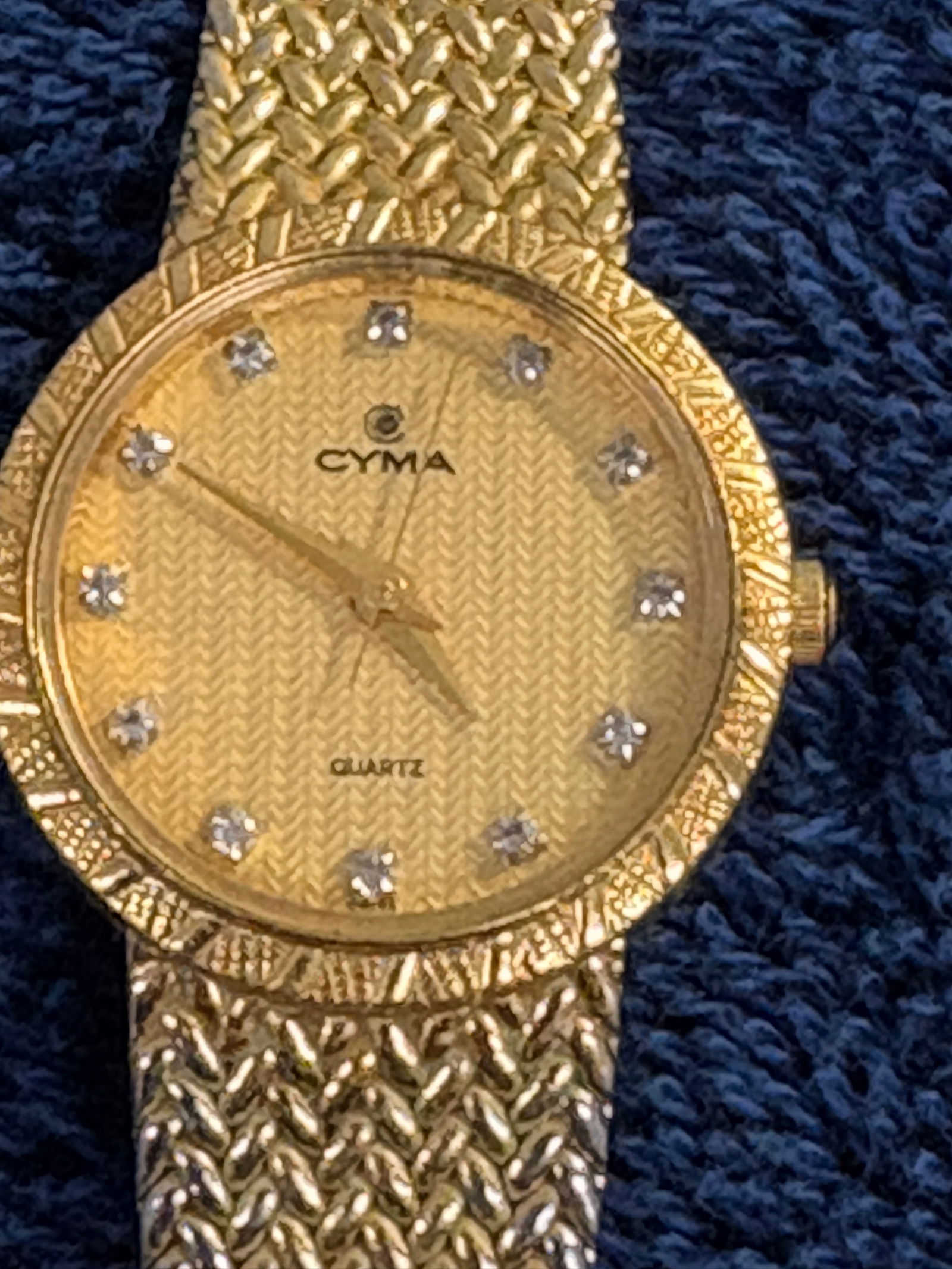 CYMA Quartz Gold-Tone Watch: Classic CYMA dress watch with textured gold dial and crystal hour markers, paired with woven gold-tone bracelet. Recognized Swiss name—attractive vintage-style fashion watch with modest collector