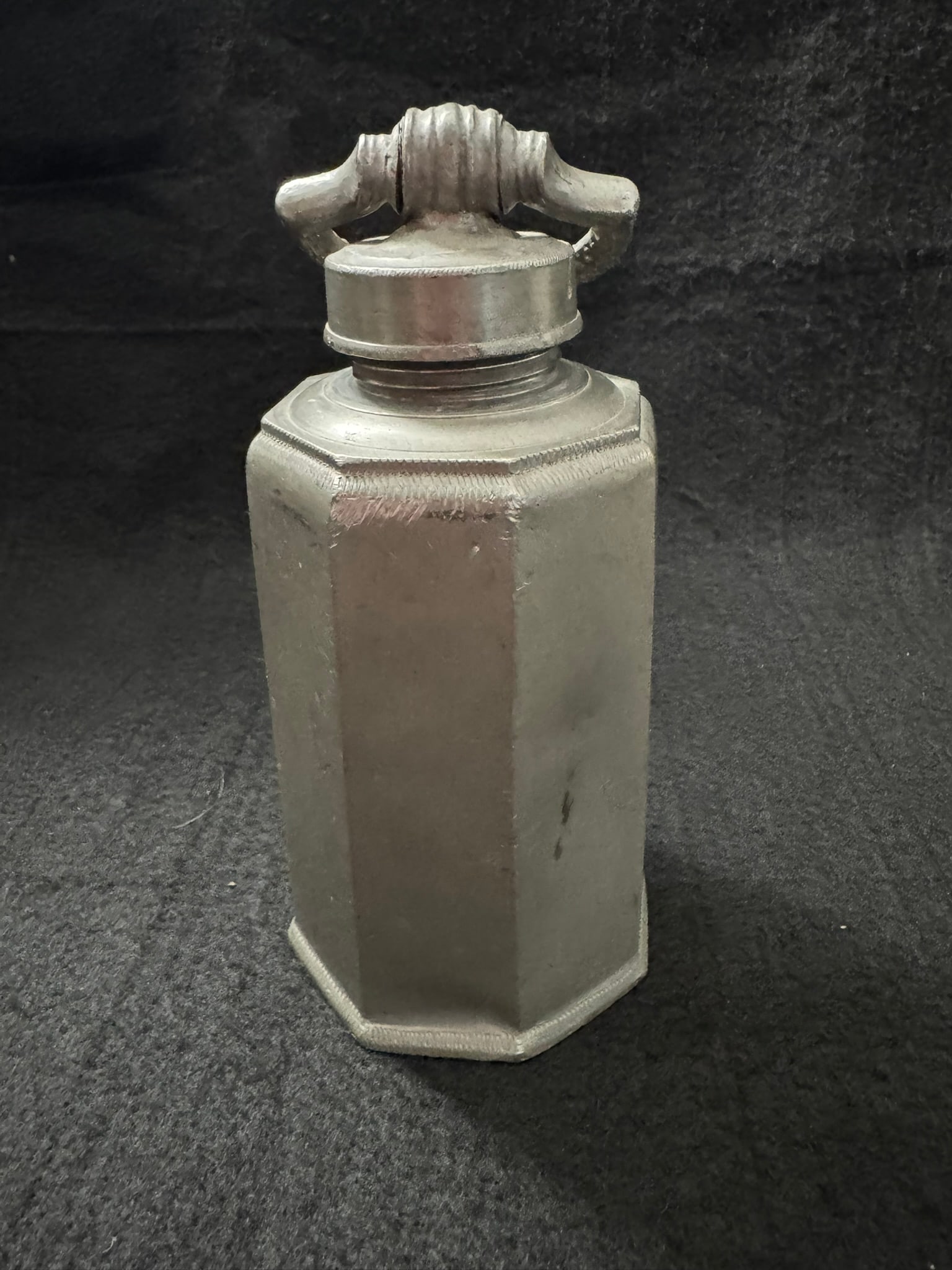 Antique Hexagonal Pewter Flask with Threaded Cap – Decorative Handle: This is an unusual and early antique pewter flask featuring a distinctive hexagonal form with a threaded neck and a matching screw-top lid. The flask is crafted in a primitive casting style, with visi