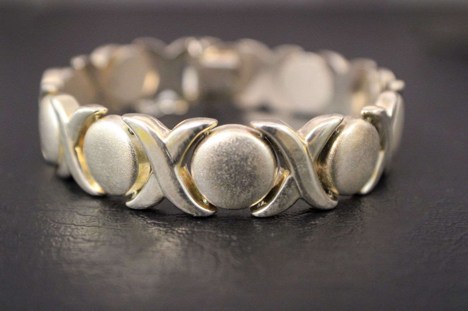 Sterling Silver X's and O's Bracelet: This charming sterling silver bracelet features a classic X's and O's design, symbolizing hugs and kisses in a timeless style. Crafted with polished links, it offers a bold yet elegant look. The brace