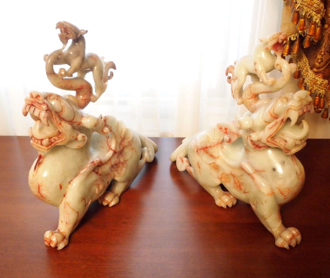 Pr hardstone guardian figures: A pair of Indonesian hardstone guardian lion sentinel figures. Light green with red veins, each carved baring teeth, surmounted by a smaller lion. One small lion with chipped front paw; the other larg