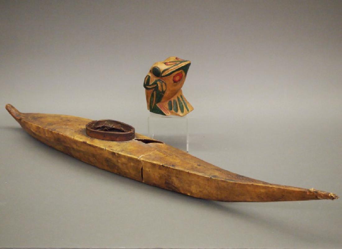 Inuit seal kayak, Haida frog: Two Northwest Coast items. Including 1 Inuit model kayak, wood framework with seal skin exterior, and 1 Haida carved wood seated frog, painted red, black and green, signed "Queen Chalotte [sic] Island