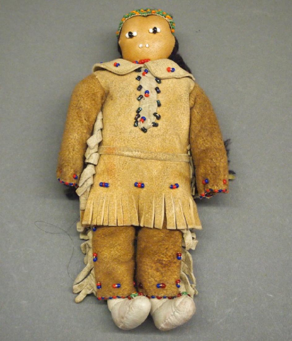 American Indian Beaded doll: A Native American Indian beaded hide doll. Probably Plains, having a leather face and dressed in hide tunic and pants, adorned with blue, red, green, orange, and white beads, with braided black yarn h