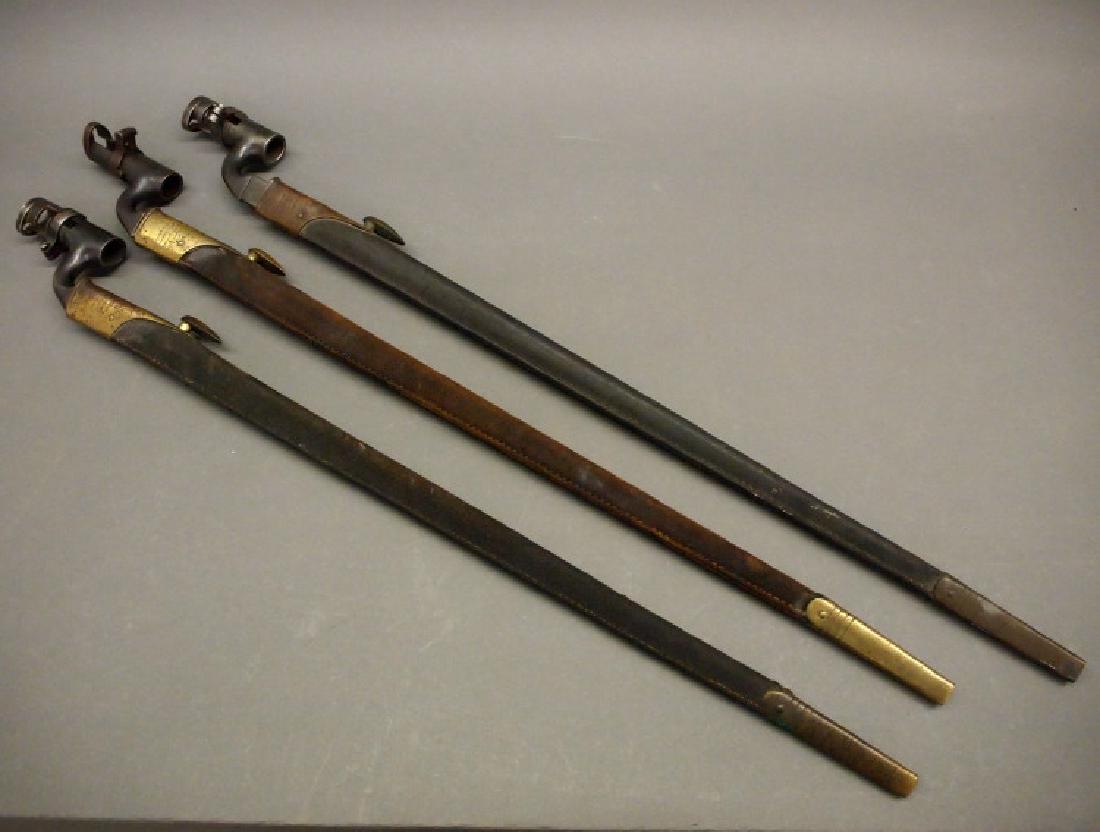 Three socket bayonets with scabbards: Three antique British socket bayonets with scabbards. Probably M1853, all are similarly well-marked, including a broad arrow over "WD", crown with letter E, and various numerals, and fitted within a l