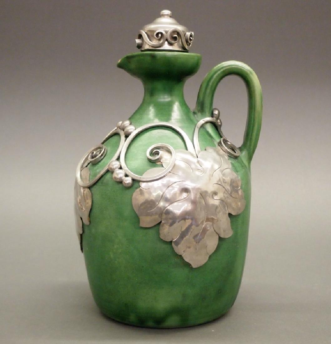 Herman A. Kahler wine jug: Herman August Kahler, Danish, 1846-1917. Ceramic jug with green glaze and applied Silver scrolling grape vine motif, fitted with matching stopper. Incised "HAK" initials at and "Denmark" encircled at
