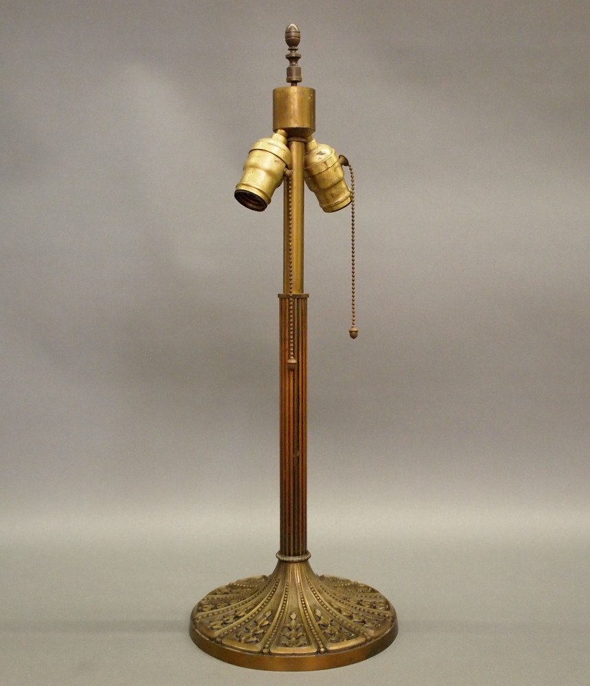 Miller Lamp Base: A Miller Patinated Metal Lamp Base. Reeded standard on a round foot with stylized bellflower and bead motifs, having a brassy patina. Raised "Miller, 1078" mark on the base. Condition C; missing heat