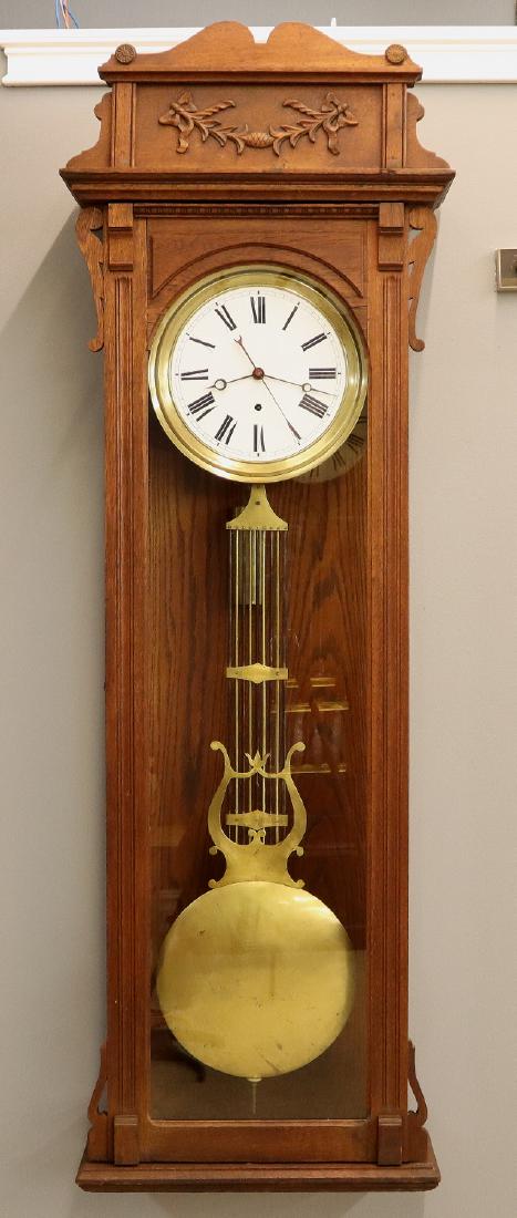 Jeweler's Regulator wall clock: A turn century Jeweler's "Pin Wheel" Regulator wall clock. 8-day time only weight driven movement with Pin Wheel escapement, compensating pendulum and porcelain dial. American Oak case with a carved c