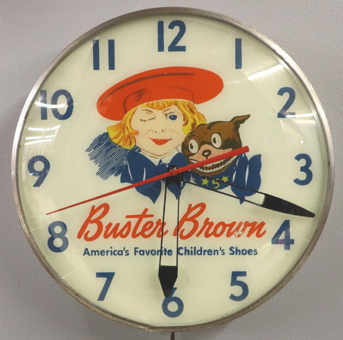 Buster Brown Shoes Clock: A mid 20th century Buster Brown Shoes Advertising Clock. Round, electric clock reads "Buster Brown America's Favorite Children's Shoes" on dial. Clock runs and lights up, some wear. 14 3/4" diameter.