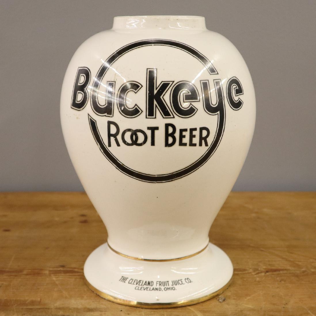Buckeye Root Beer Syrup Dispenser: An early 20th century Buckeye Root Beer Soda Fountain Syrup Dispenser. Having a baluster form porcelain body with applied lettering. Lacks pump, some wear and edge damage. 11" high. ESTIMATE $200-400