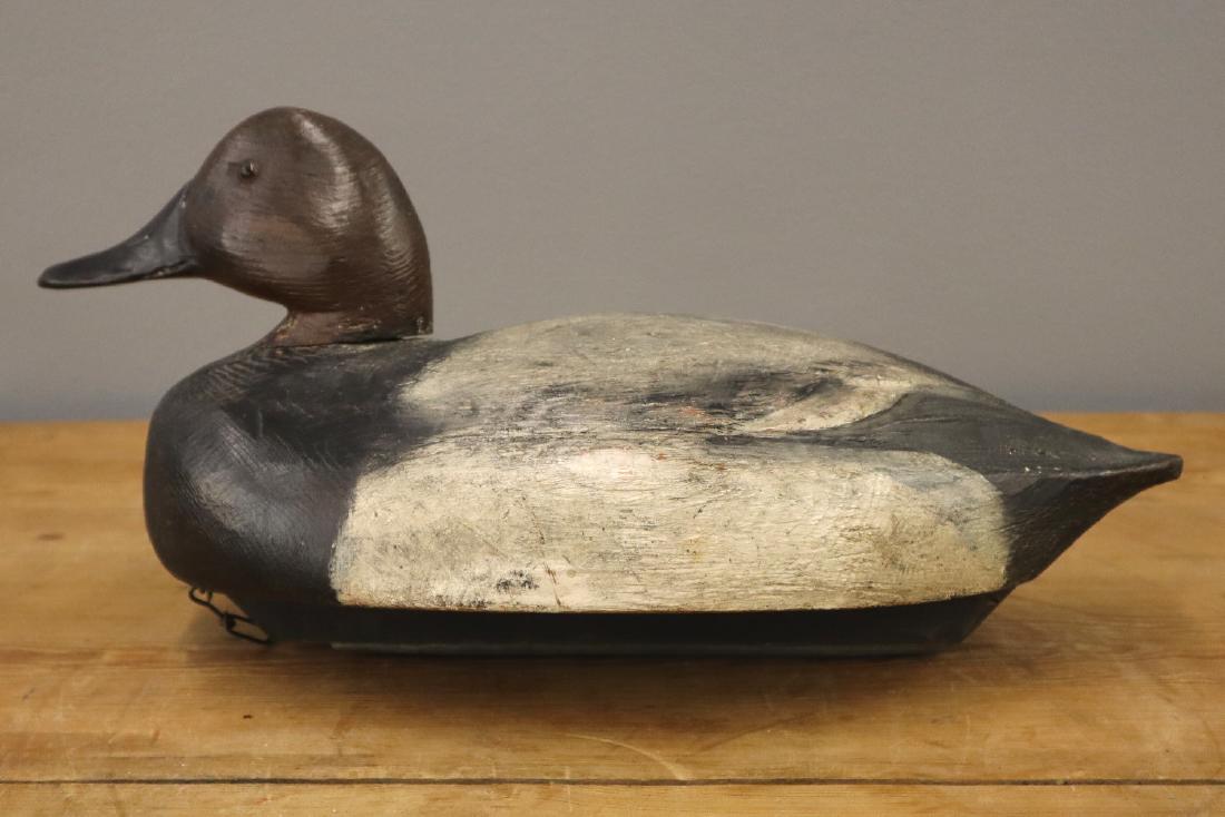 Ben Schmidt Canvas Back Drake Decoy: A Ben Schmidt Canvas Back Decoy. Carved wood duck decoy with original paint, glass eyes, and carved details on the beak and at the back and tail. A painted red "H" is at the underside; includes weight