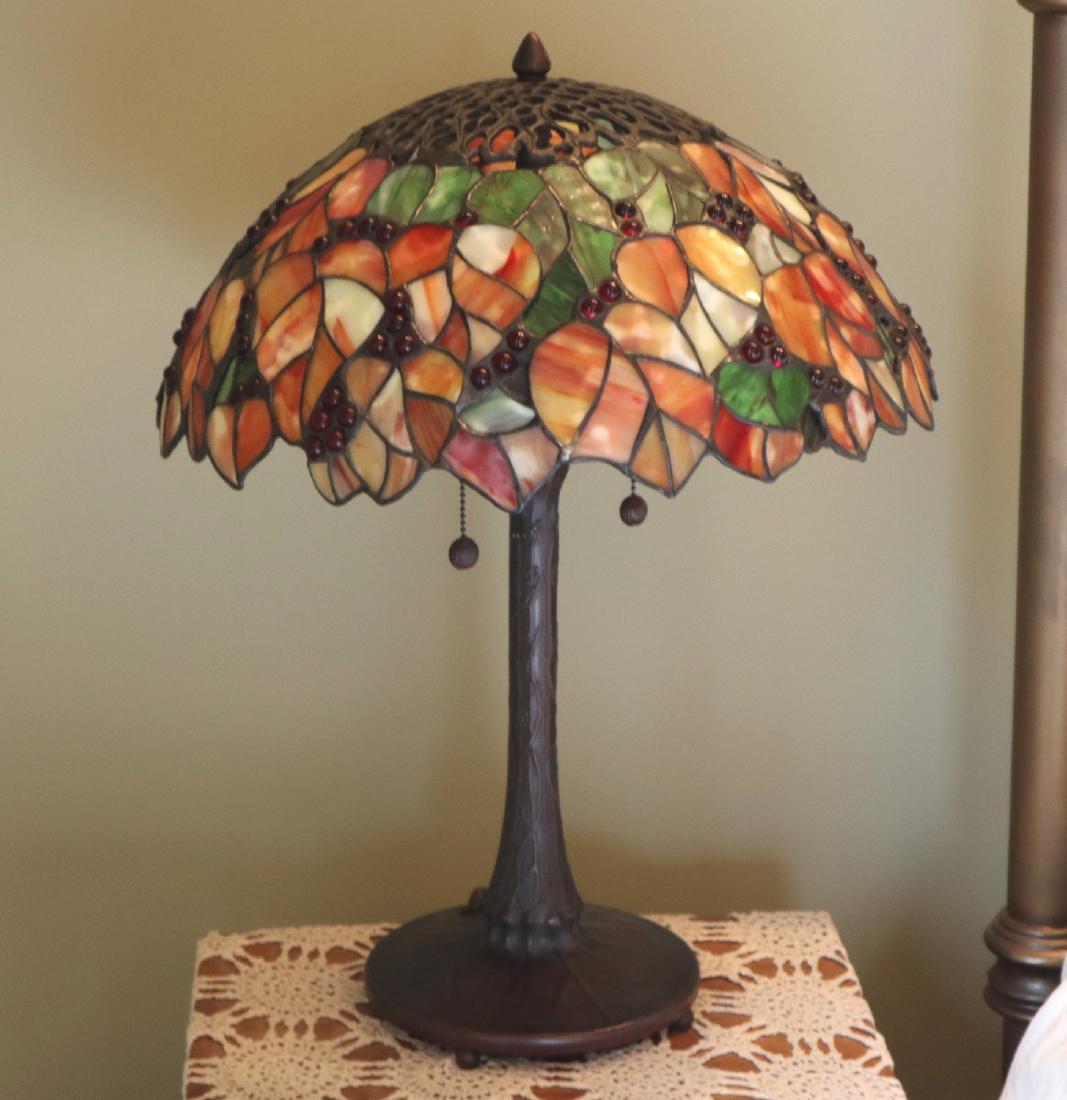 Stained & Leaded Glass Lamp: A Contemporary Stained & Leaded Glass Lamp. Glass shade with leaf motif and cabochon glass accents and a patinated metal base. Light wear. 17 1/2" x 22" h. ESTIMATE $200-400