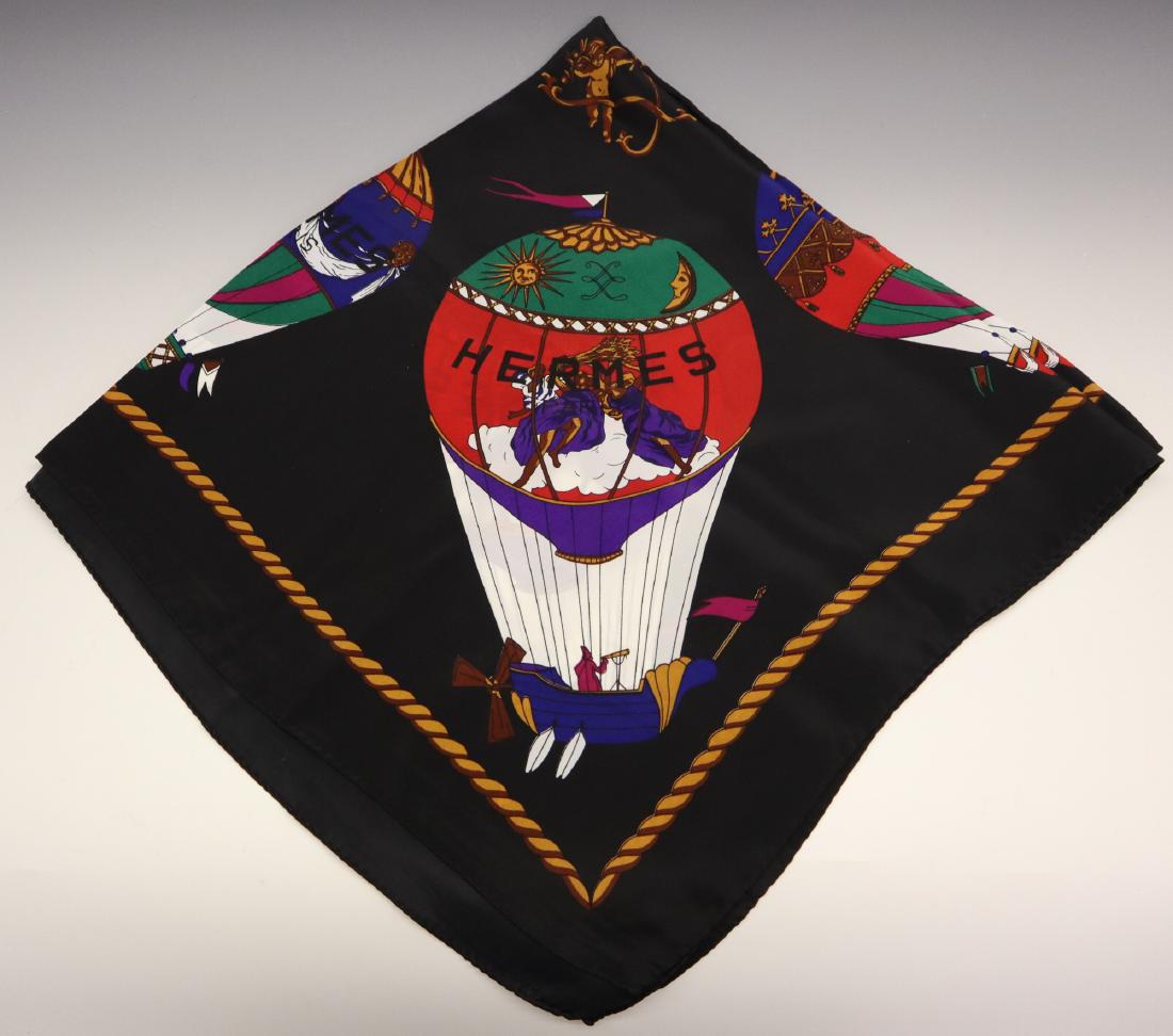 Hermes Silk Scarf: An Hermes Silk Scarf. Having a black ground with a Hot Air Balloon motif in multiple colors. Marked "Hermes Paris" within the scarf and includes a label that reads "100% Seta-Soie Reine Seide T.K Silk
