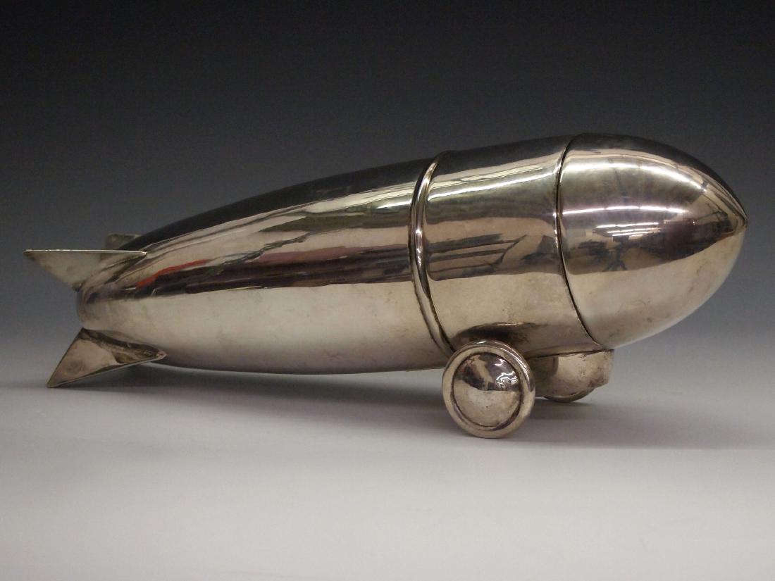Art Deco Zeppelin Cocktail Shaker: An Art Deco Silver Plate Zeppelin Cocktail Shaker. In three pieces. Unmarked. Light wear and slight surface scratches noted. 12" long. ESTIMATE $200-300
