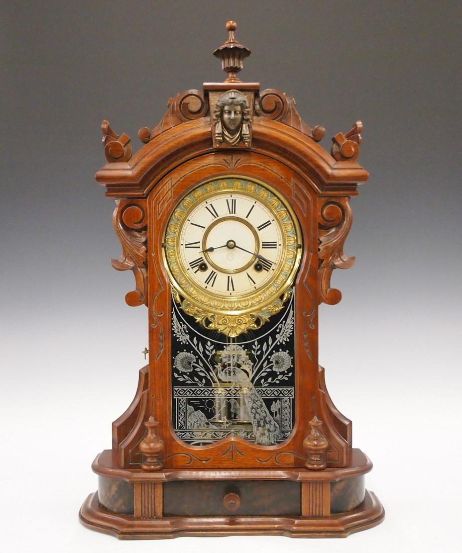 Ansonia Monarch Shelf Clock: A late 19th century Ansonia "Monarch" model shelf clock. 8-day time & strike movement with paper dial and cast Brass bezel with painted detail. In a Walnut case with carved crown, turned finials and s