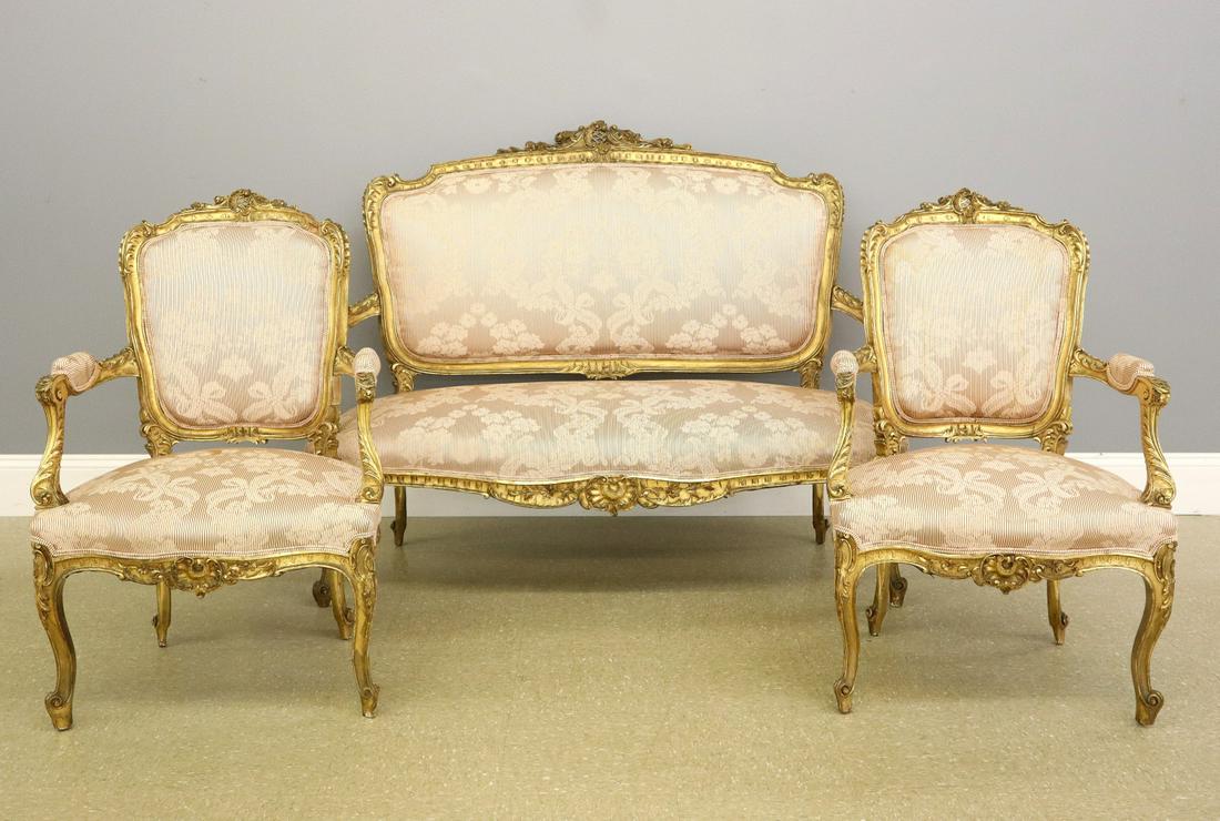 French Settee & 2 Armchairs: A 19th Century French Louis XV Style Settee & Two Armchairs. Featuring shaped backs with carved detail, open arms, shaped skirts and cabriole legs. Original gilded finish with wear; upholstery with we