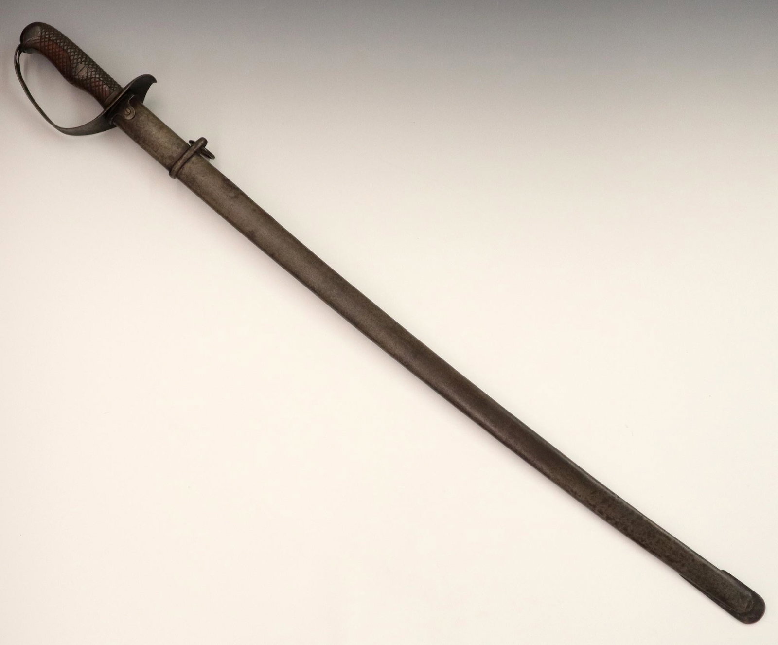Japanese Sword: A Japanese WWII Cavalry Sword. Having a checkered metal and carved wood hilt and simple metal guard. Stamped "7165"; includes metal scabbard. Wear to the metal overall, some light scratches and pittin