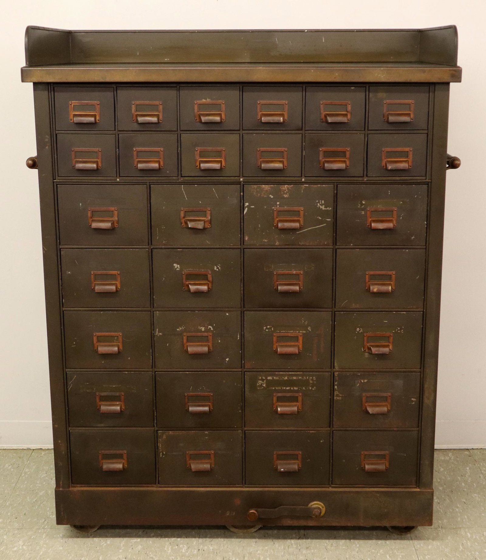 Industrial Steel Cabinet: A 1940's Industrial Steel thirty two drawer roller cabinet. Steel work surface with short backsplash over twelve small and twenty larger drawers, side handles and lower wheel lock lever. Original Dark
