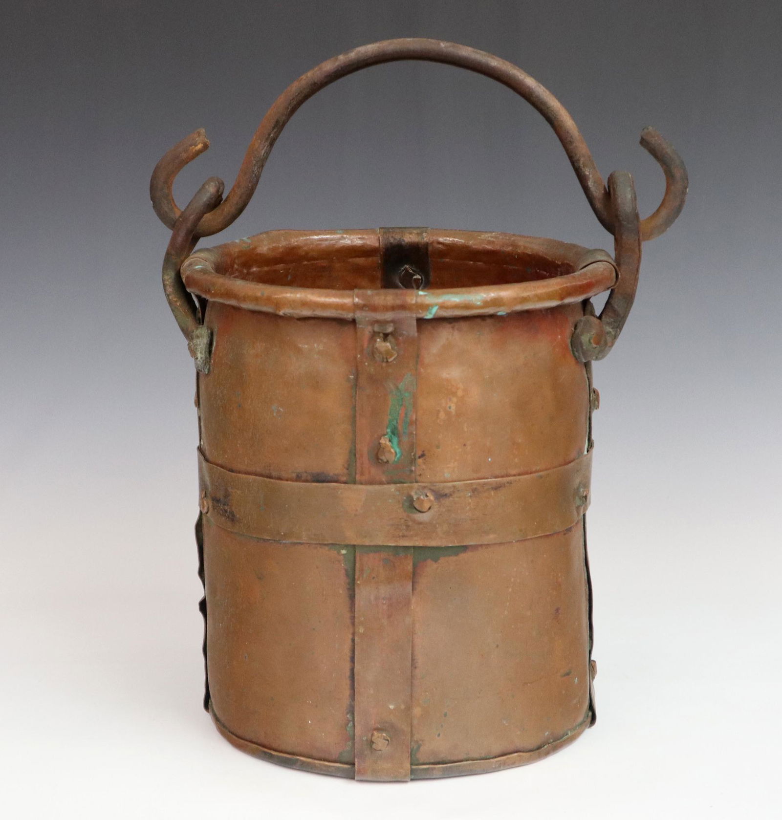 Copper Kettle: A large turn of the century Copper cooking kettle. Dovetailed construction with strap reinforcement and forged iron handle. Wear and some denting. 12" high. ESTIMATE $50-75