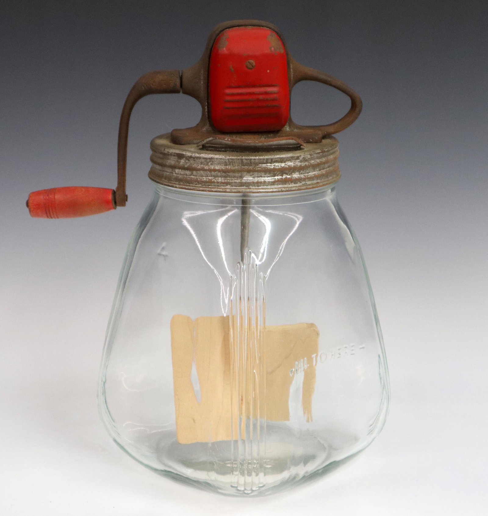 Glass Butter Churn: An early 20th century "S C C" American glass butter churn. Molded glass body (marked "4") with a metal cover and crank with wooden paddles. Some wear, pain loss to cover. 12 1/2" high overall. ESTIMAT