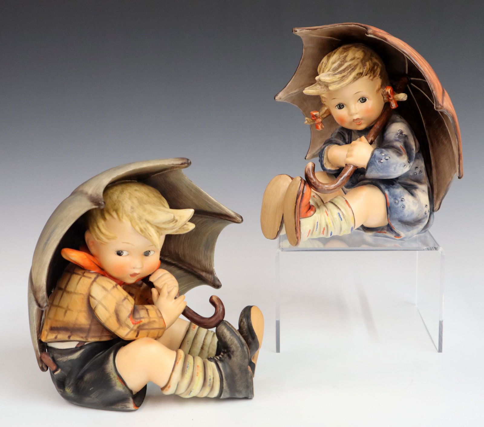 2 Goebel/Hummel Figures: Two Goebel/Hummel porcelain figures with hand painted decoration. "Umbrella Boy" #152-A and "Umbrella Girl" #152-B. Printed and impressed marks, various ages. Slight wear to paint. Each 7 3/4" high. E