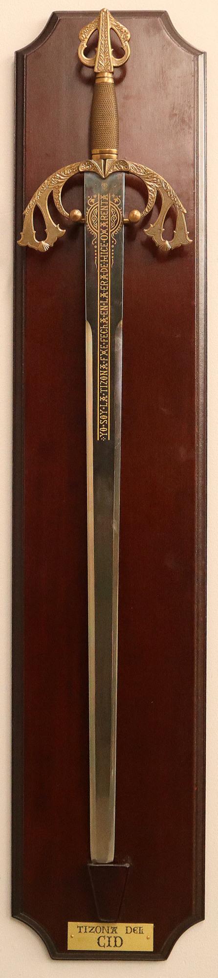 Replica Sword: El Cid Replica Sword. Plaque reads "El Cid Tizona" by Marto of Toledo, Spain, on a Mahogany plaque. Minor wear and tarnish overall. Sword is 37 1/2", plaque is 42 1/2" long. ESTIMATE $100-200