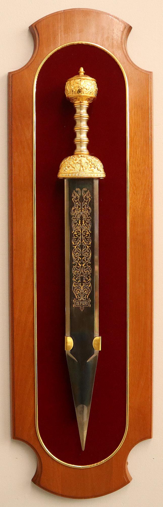 Franklin Mint Sword: Franklin Mint Commemorative "The Sword Of Julius Caesar" Replica Sword. Decorative engraving on the blade along with "SPQR", mounted on a Mahogany plaque. Minor wear and tarnish overall. Sword is 27 1