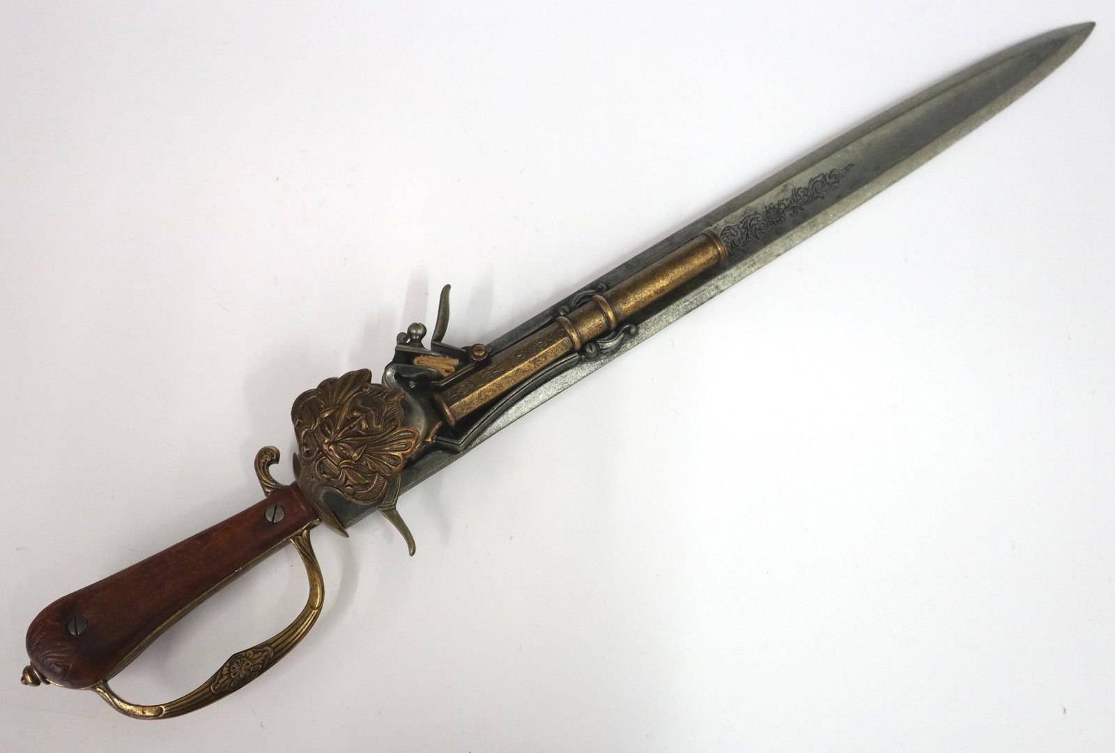 Replica Sword/Pistol: Replica Sword/Flint Lock Pistol combination. Short sword with flintlock pistol mounted at one side and a Walnut grip. Unmarked with minor wear overall. 25" long. ESTIMATE $50-100