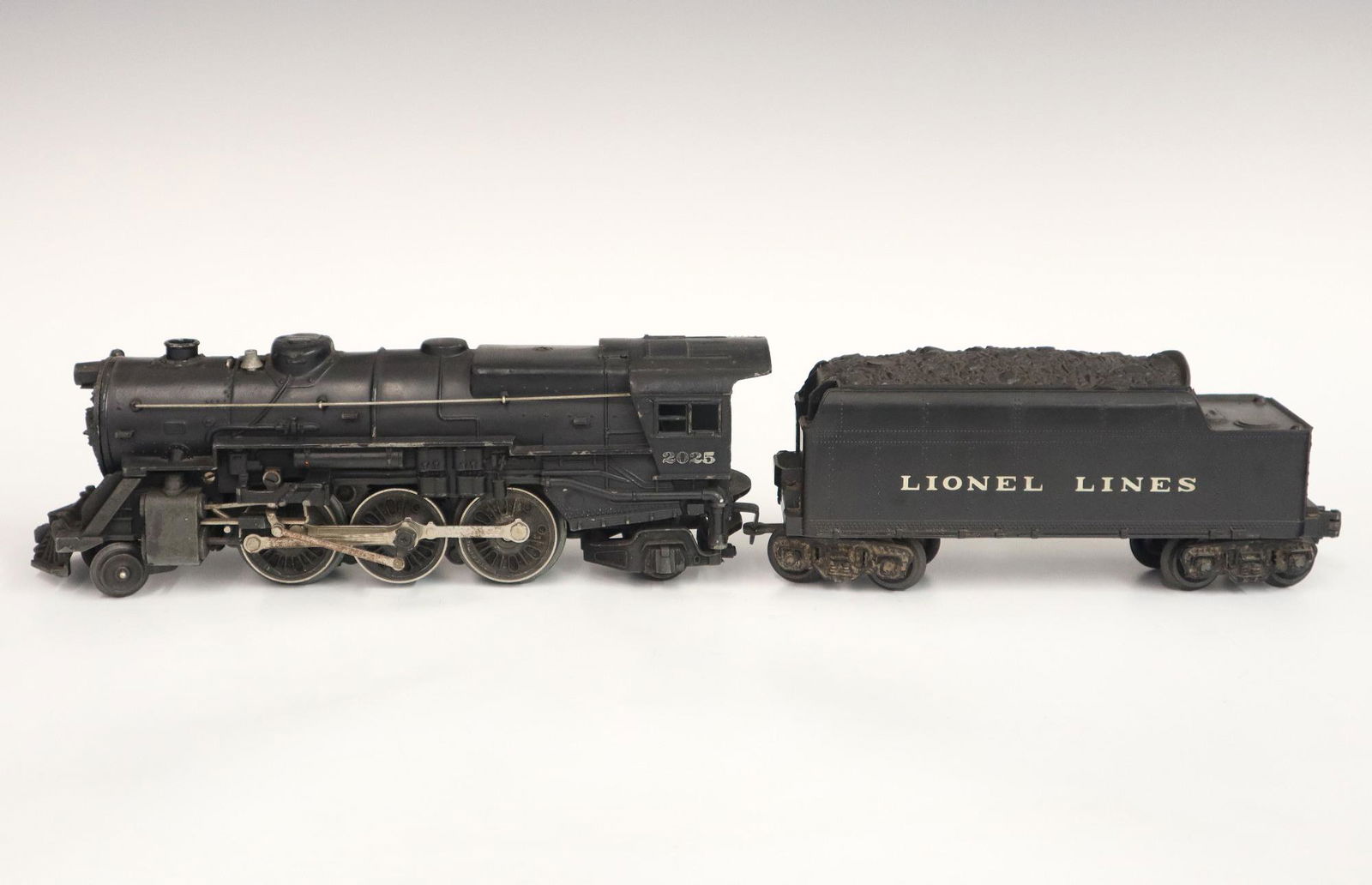 Lionel Locomotive and Tender: A Post-War Lionel O Gauge Locomotive #2025 with Original Tender. Minor wear and paint loss, minor chip on tender. 18" long. ESTIMATE $50-100