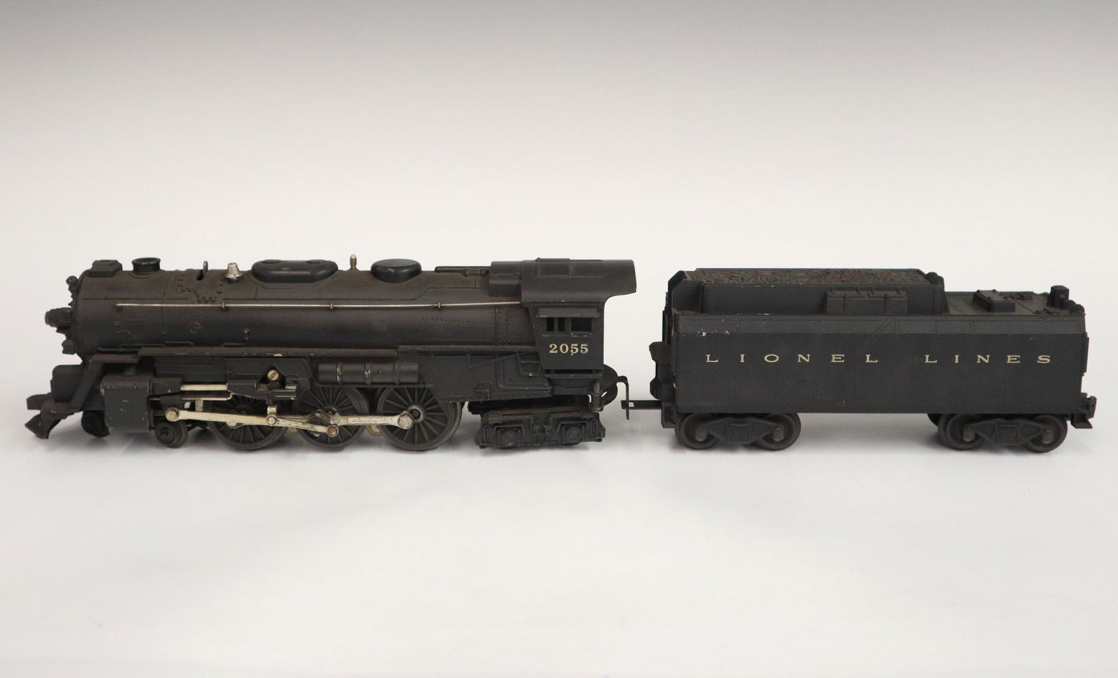 Lionel Locomotive and Tender: A Post-War Lionel O Gauge Locomotive #2055 with Original Tender. Minor wear and soiling. 19" long overall. ESTIMATE $50-100